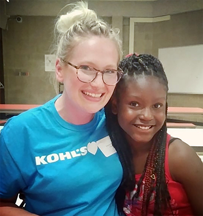 Emma Harris visits with a student while volunteering with other Kohl’s employees last summer at a Milwaukee school.