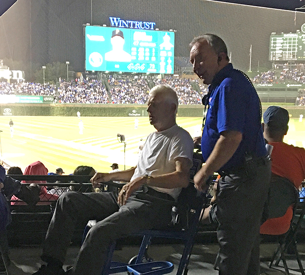 Chuck Young, who earned degrees from UW-Stout in 1971 and 1972, helps a fan at Wrigley Field in Chicago.