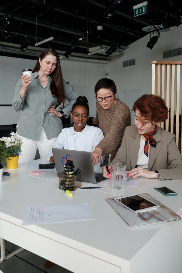 Four people sitting at a desk around a laptop