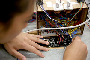 A Robotics REU student works on wiring as part of a meal assistance robot.