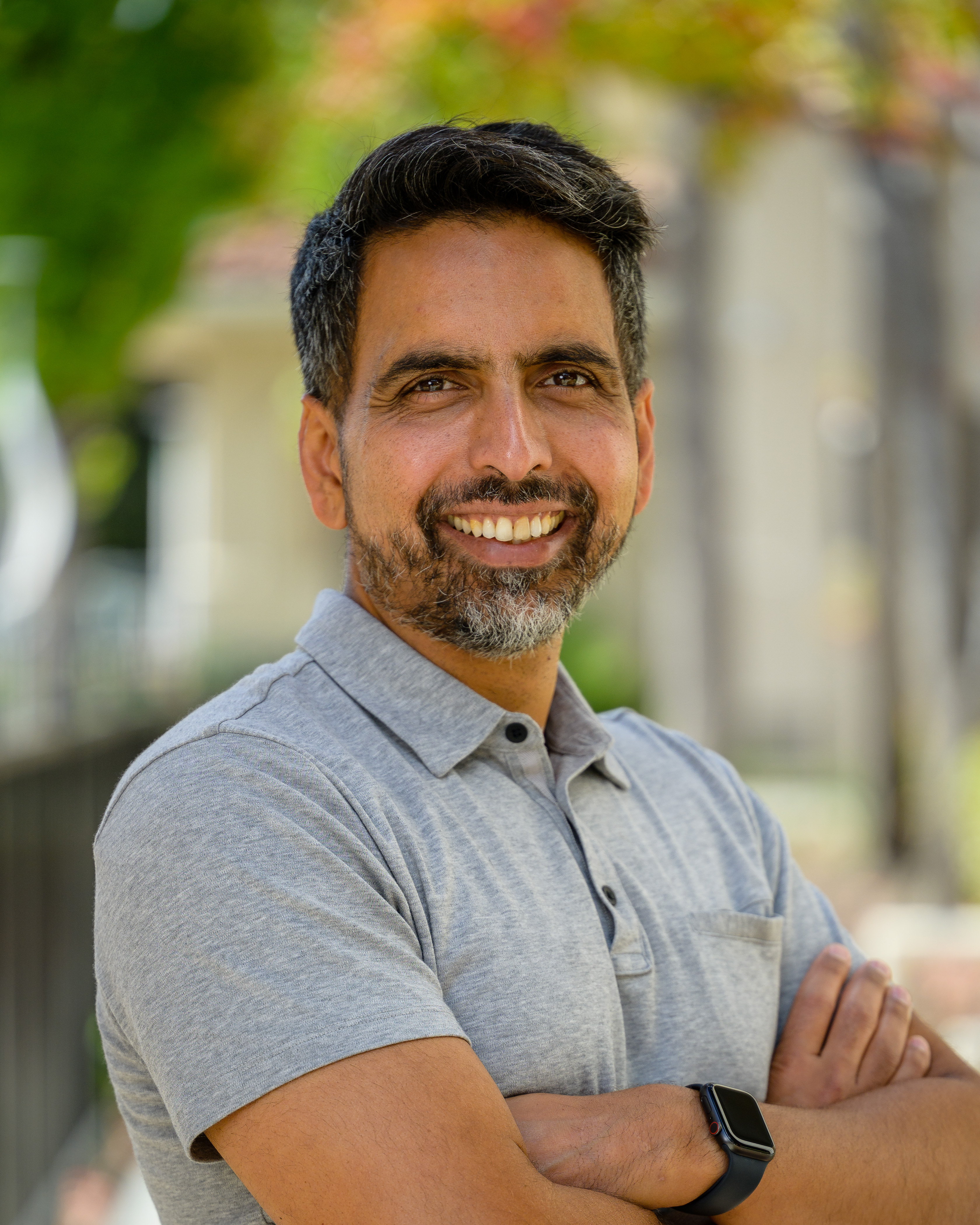 Sal Khan is wearing a gray polo and smiling at the camera