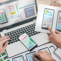 A laptop open showing a wireframe of a mobile website, with different wireframes sketches.
