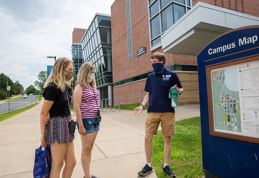 An Admissions Office guide wears a mask and carries sanitizer spray while conducting a tour for new students at UW-Stout.