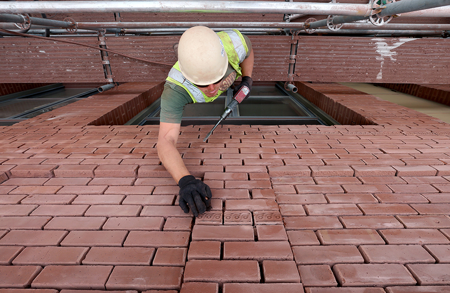 A mason repairs bricks at Bowman Hall.