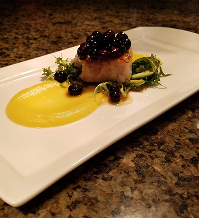 An entrée prepared by Halverson includes pork belly with frisee, acorn squash puree and marinated huckleberries.
