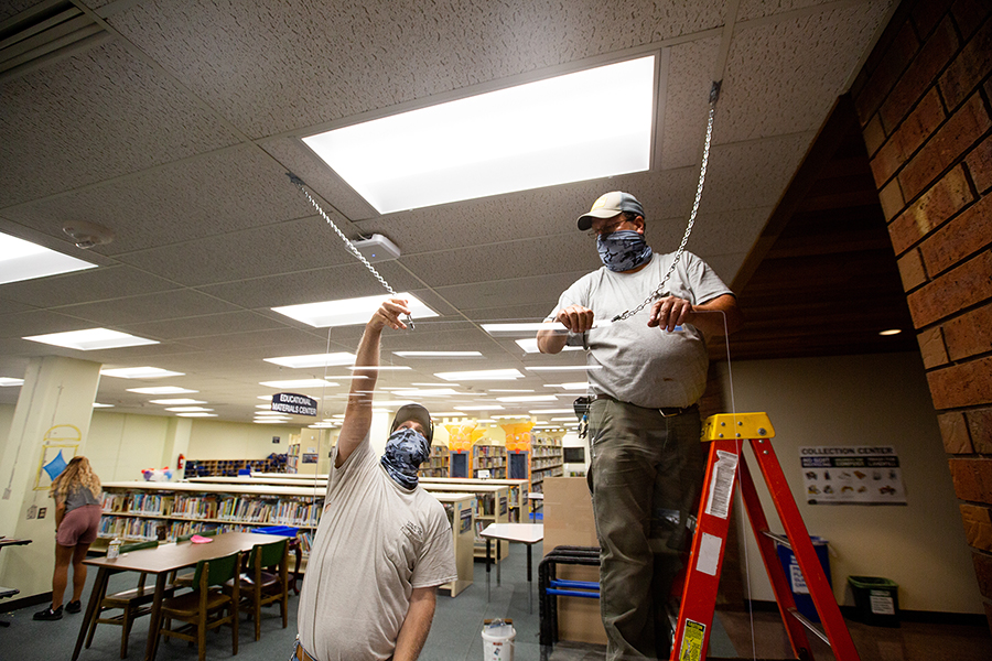 Staff at UW-Stout install a clear barrier in the University Library. 
