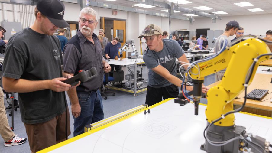 Students work to control a FANUC robot with help from instructor Paul Craig