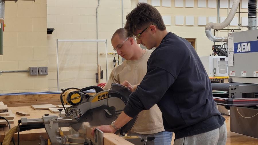 Students use a miter saw to cut 4x4 posts in the Woods Lab