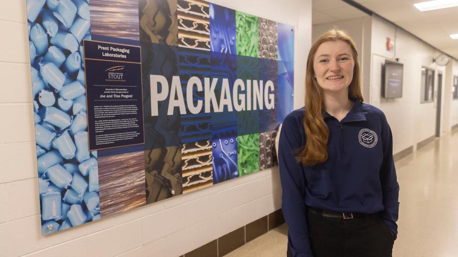 A student poses in front of the Packaging Lab sign.