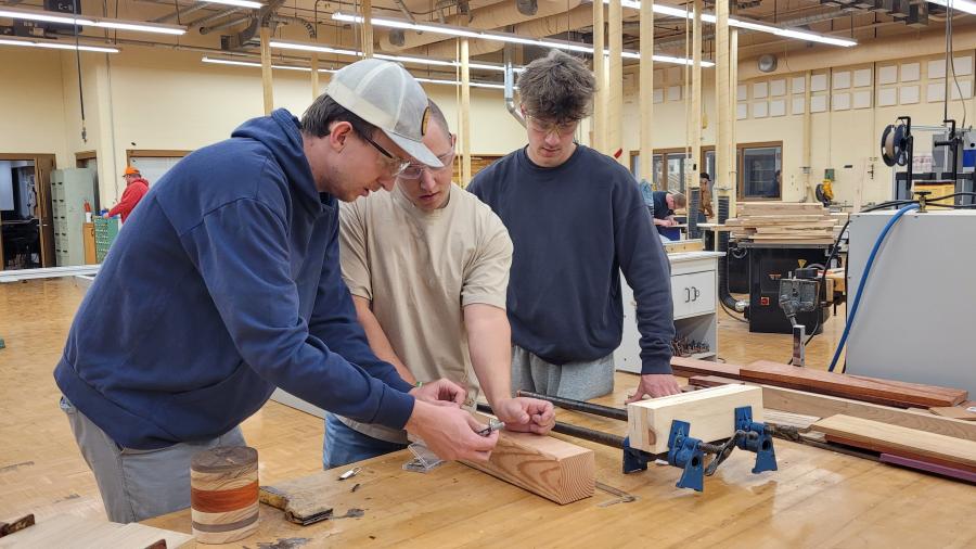Students attach 3D printed fasteners to a bedpost in the Woods Lab
