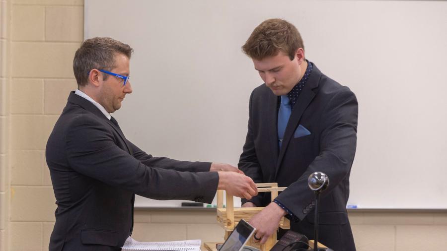 Students display a wooden model.