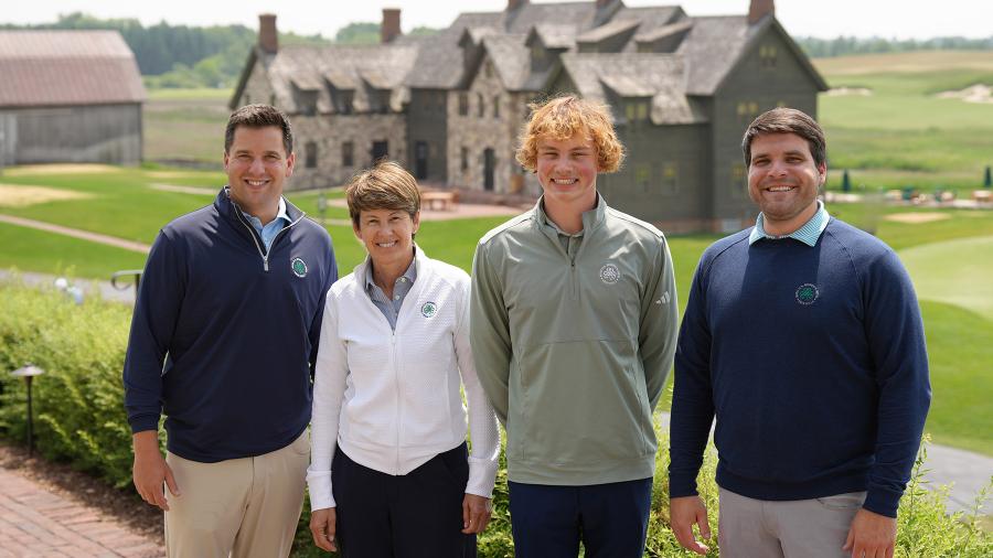 Four people stand outside a golf club house
