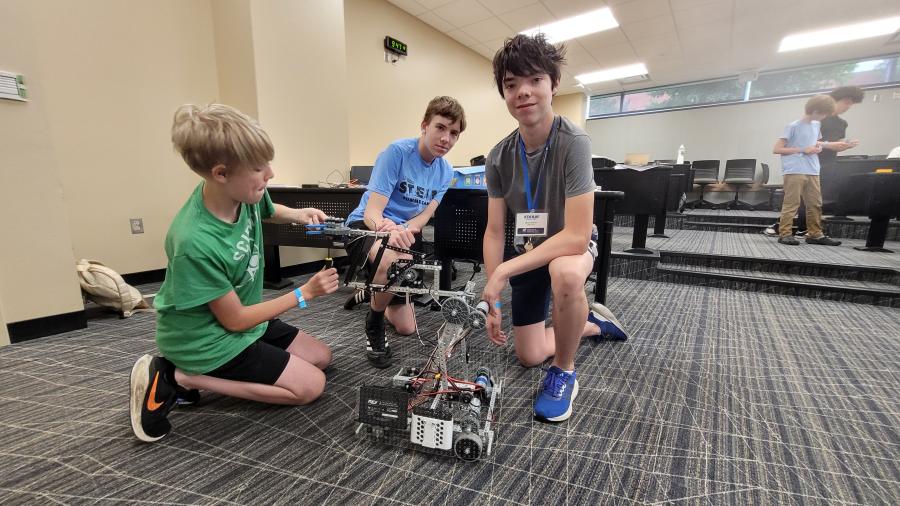 Three students pose with the robot they designed