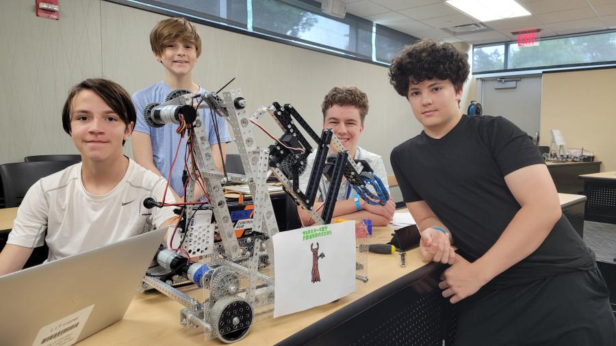 Four students pose with the robot the designed
