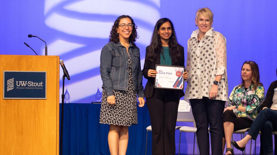 Three women stand on a stage