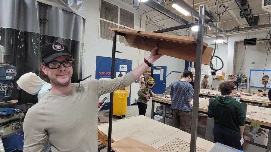 An industrial design student displaying the shelving their self-designed entryway assistant.