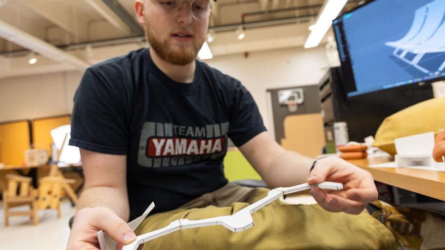 Aaron Hoyt showing a mini prototype of the support structure for a collapsible chair