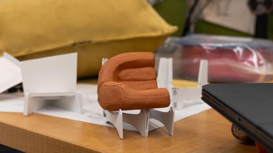 A clay and paper mini prototype of a collapsible chair