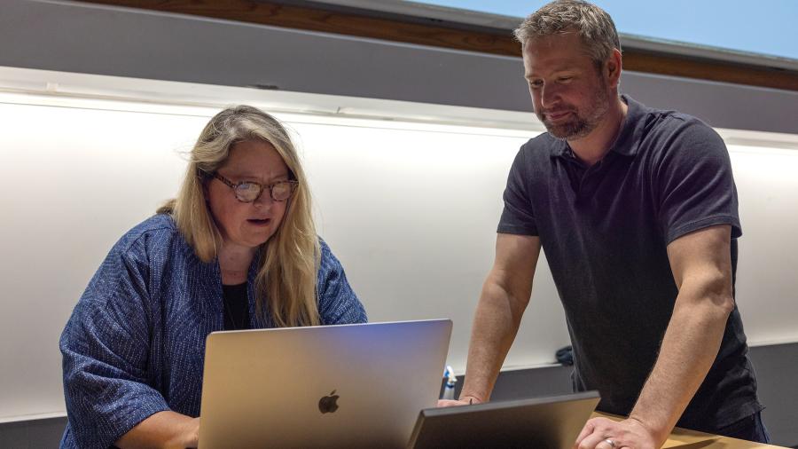 Two people look at laptop