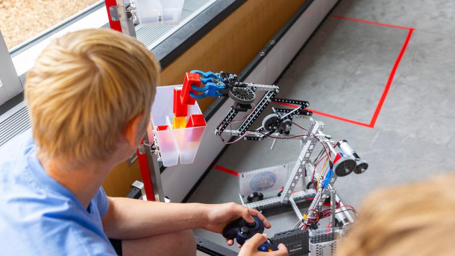 Students complete obstacle course challenges with small robots they built.