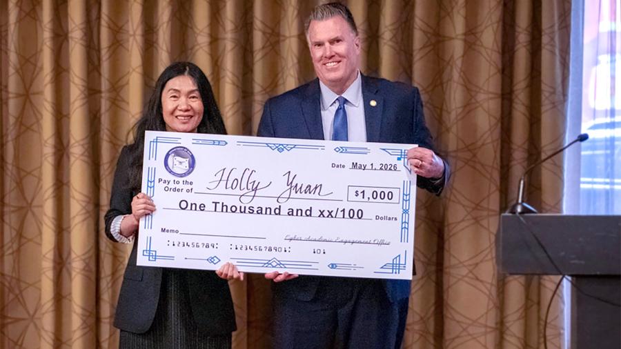 Two people hold large check