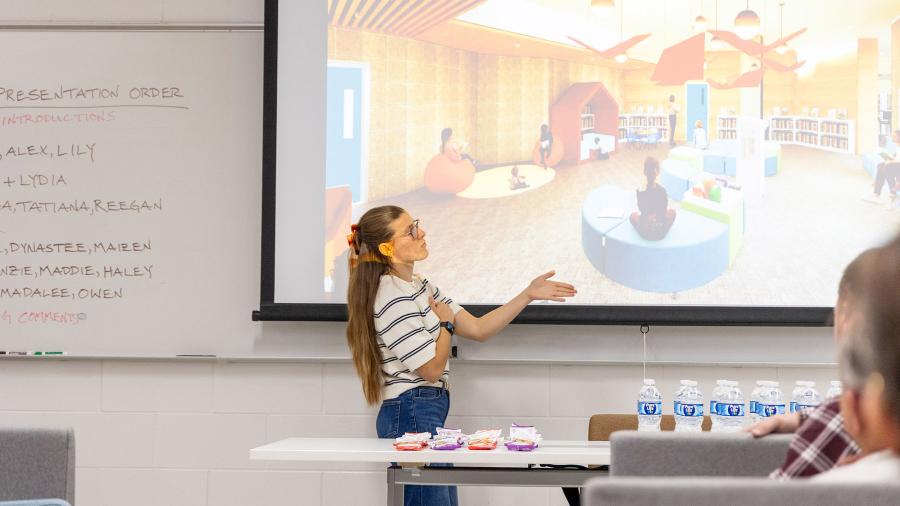 Student speaks in front of projection screen