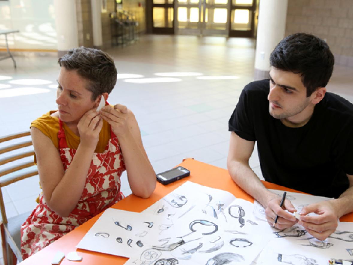 UW-Stout Associate Professor Jennifer Astwood, left, and visiting Russian scholar Azamat Tavitov try a prototype of a sensory safety device that would fit over a person’s ear.