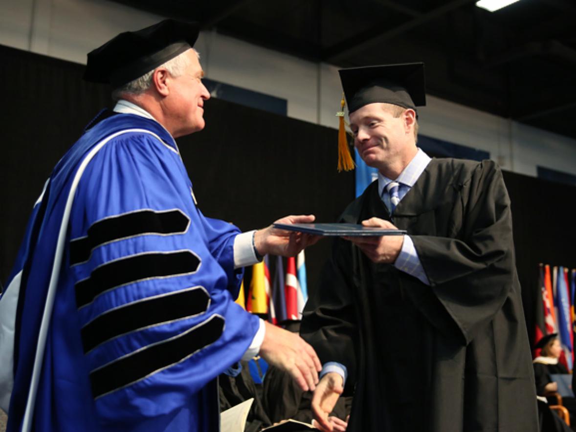 Melvin Winberg receives his diploma Dec. 16 from Chancellor Bob Meyer during commencement at UW-Stout. Winberg spent parts of 17 years working toward his degree.