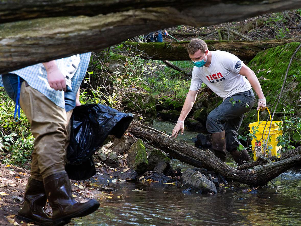 students are picking up garbage in a wooded creek
