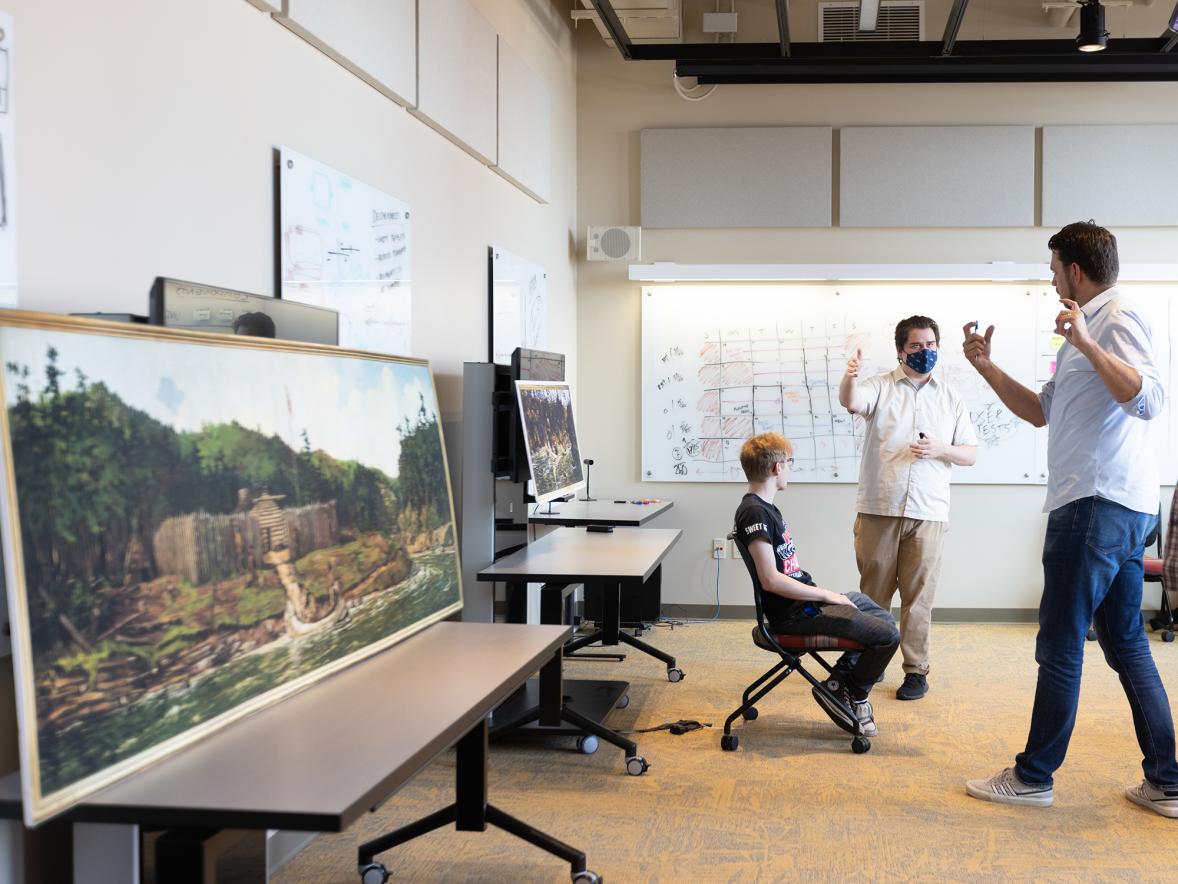 Mitch Ogden, at right, UW-Stout associate professor and program director of professional communication and emerging media, talks with students Brian Bauch, at left, and Jacob Karr about the Stout Mobile Augmented Reality Tour of Art, or SMARTArt app.