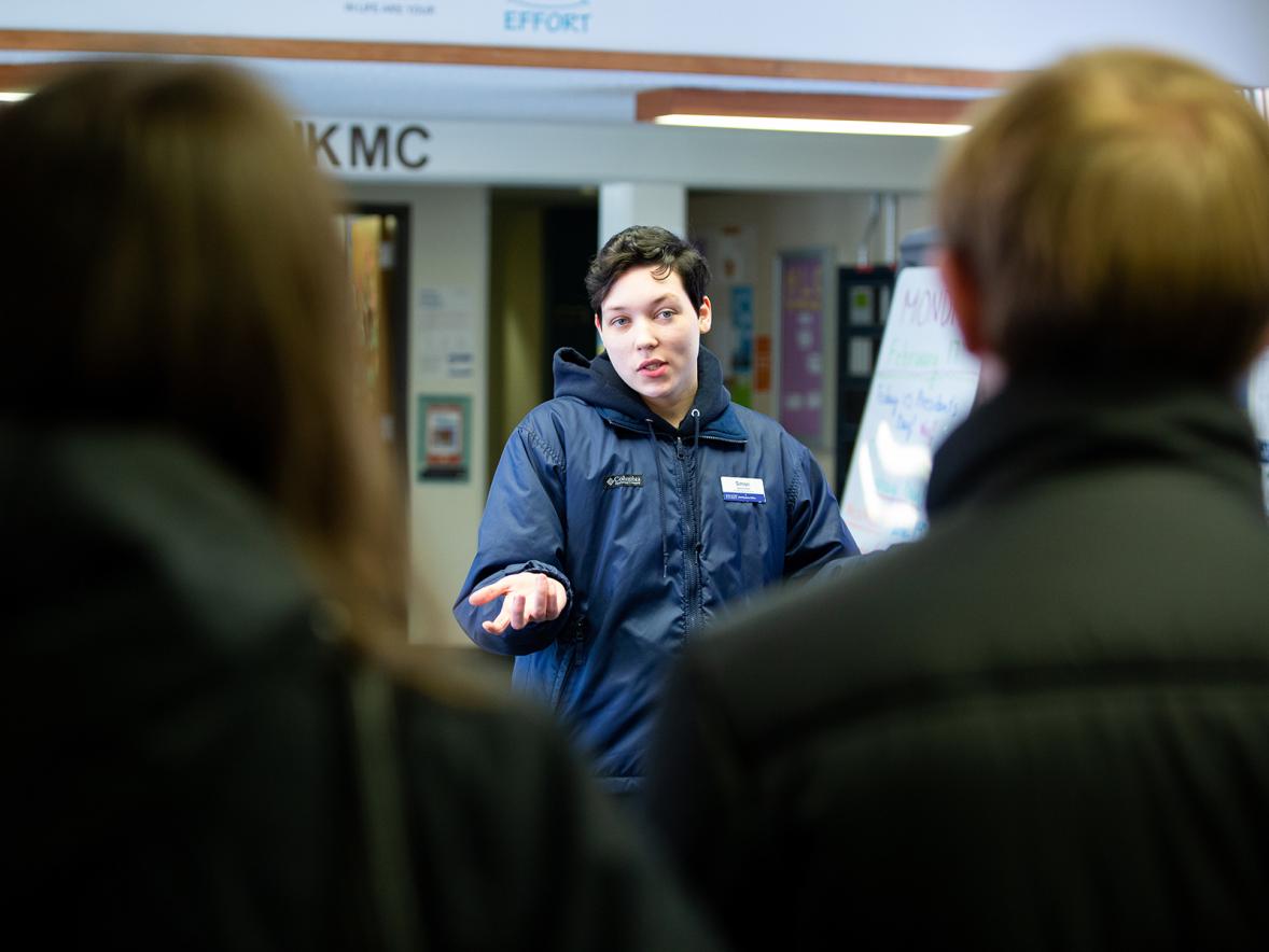 A student tour guide talks with prospective students and family members during a campus visit.
