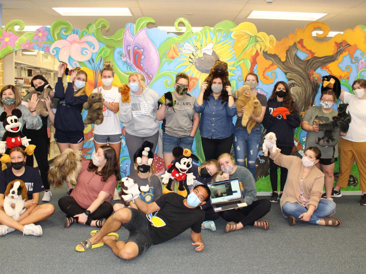 Education students with puppets in front of the garden mural at the Educational Materials Center.