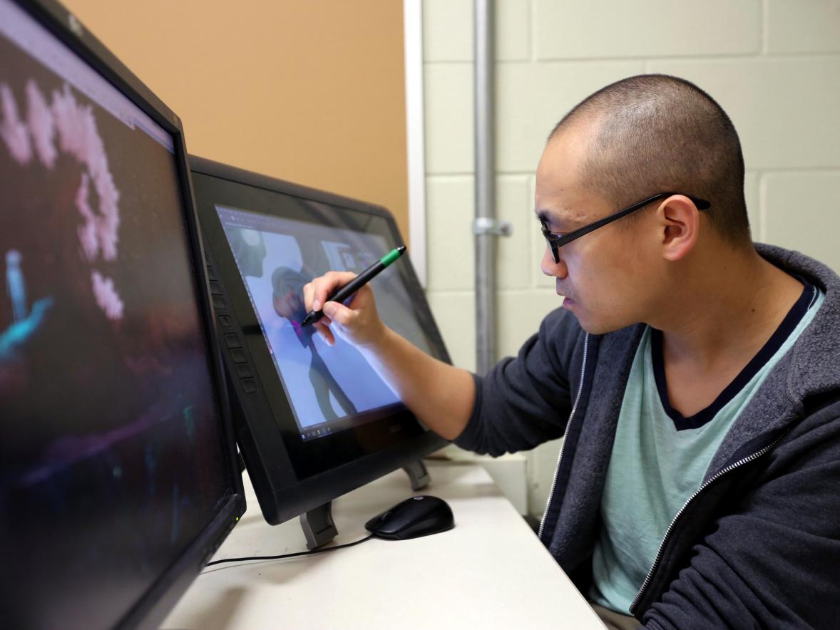 Hue Vang works in a UW-Stout game design lab. The 2018 MFA in design graduate is a matte painter for DreamWorks animation in California.