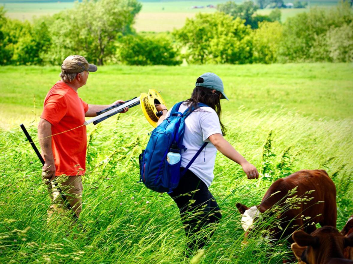 LAKES students Audrey Cho helps farmer Dan Prestebak roll out fencing.