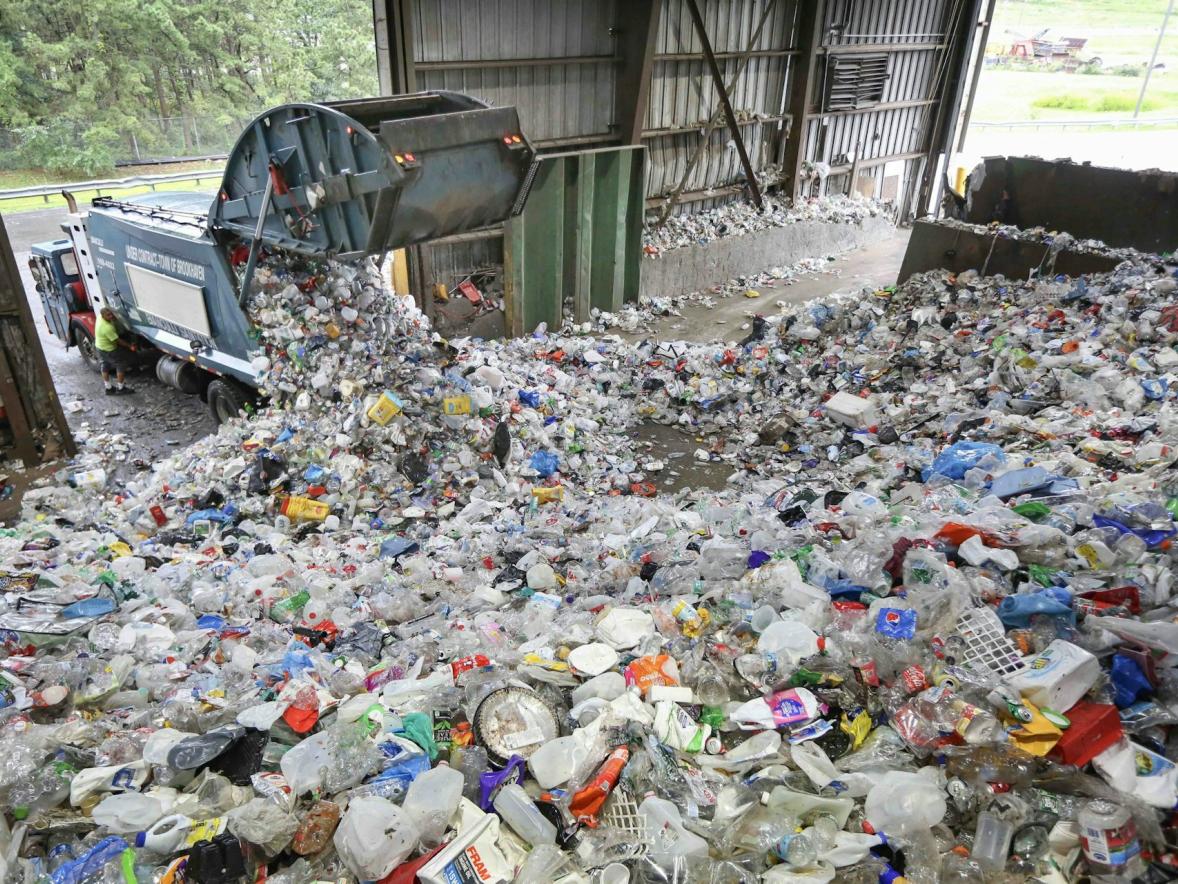 A garbage truck dumps single-use plastic at a recycling sorting plant,