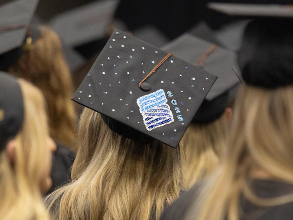 A student has decorated their cap with Stout's logo