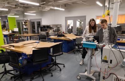 Two students stadning next to each other working together on a laptop in the Fab Lab.