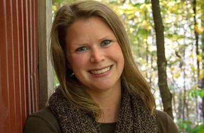 Brianne Maier poses outdoors in front of a wooded backdrop.