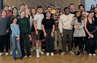 A large group of students stands together for a group photo inside a campus building.