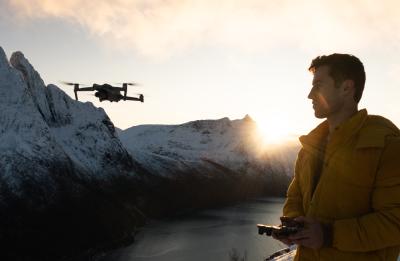 Noah operates a drone from a snowy mountain overlook at sunrise.