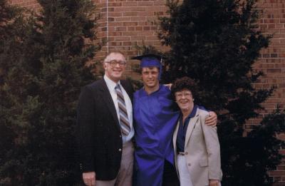 Dave Rasmussen, wearing graduation regalia, poses with two family members outside following his UW-Stout graduation in 1985.