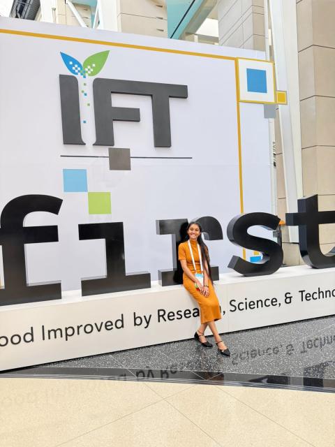 A woman sits in front of a sign