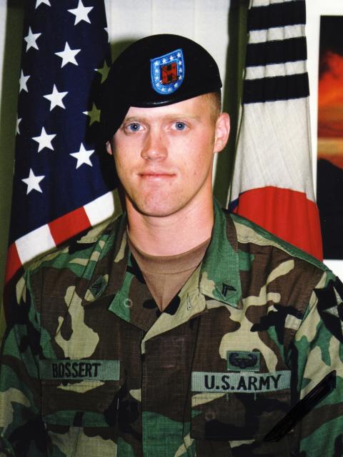 SSGT Andrew Bossert in full uniform standing in front of an American flag