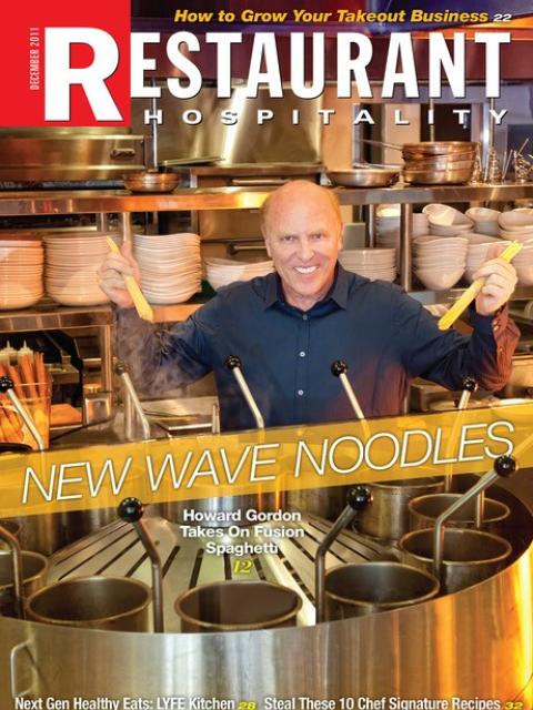 Magazine cover showing a person standing behind a restaurant cooking station holding strands of noodles above steaming pots in a commercial kitchen.