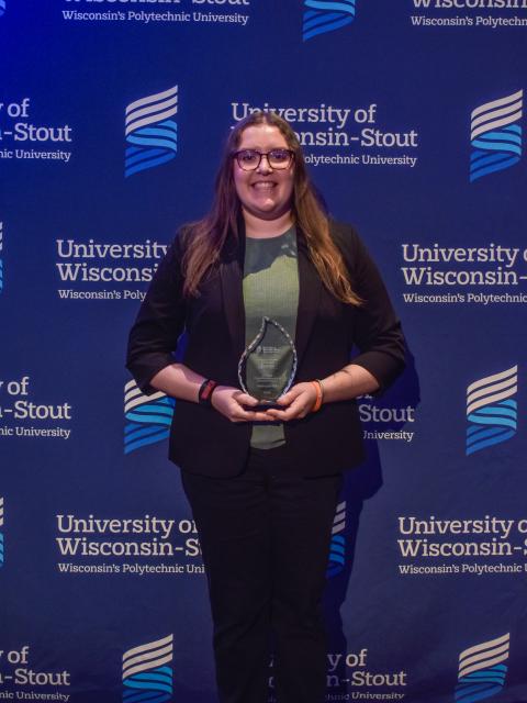 Megan stands in front of a UW-Stout backdrop holding the 2026 Co-op Education & Internship Student of the Year award.